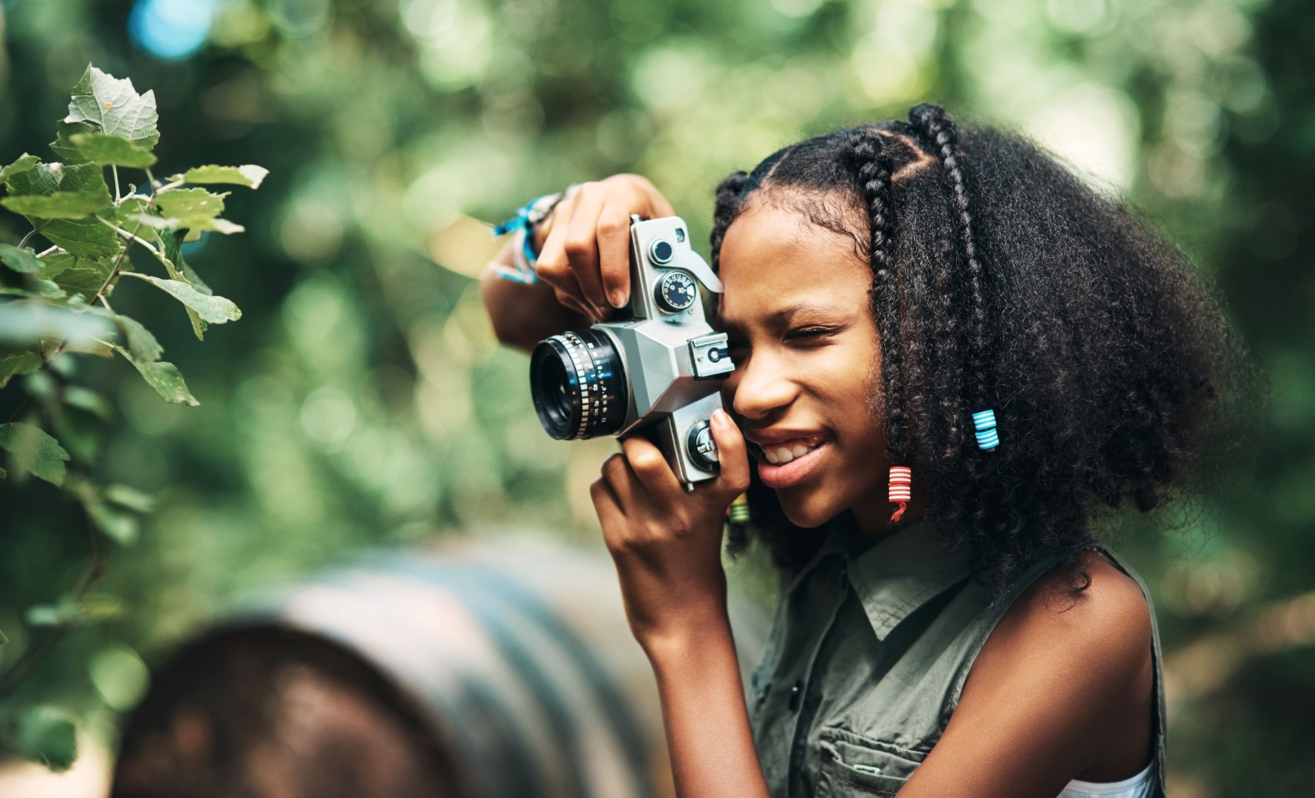 Shot of a teenage girl using a camera while hiking through the forest at summer camp